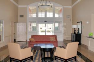 a living room with a red couch and two chairs at Extended Stay America Suites - Houston - Med Ctr - NRG Park - Braeswood Blvd in Houston