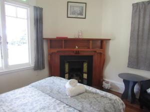 a bedroom with a fireplace with a white towel on a bed at White Elephant Accomodation in Motueka