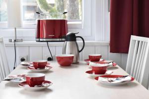 ハーネンクレー・ボックスヴィーゼにあるHenne Hahnenkleeのテーブル(赤いカップ、ソーサー、コーヒーポット付)