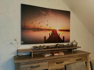 a painting on a wall above a wooden dresser at Ferienwohnung "Deluxe" in Korbach in Korbach