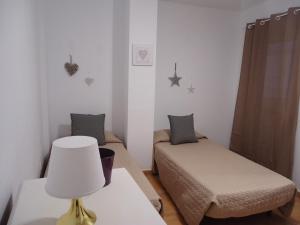 コラレホにあるApartamento Céntrico Lobosのベッド2台、ランプ1台が備わる小さな客室です。