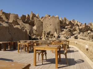 a group of tables and chairs in front of a rock formation at Albabenshal Lodge Siwa in Siwa