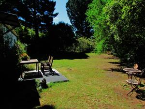 um quintal com cadeiras, uma mesa e uma mesa de piquenique em Nut Point Cottage em West Melton