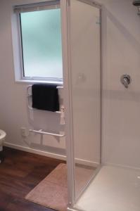 a shower with a glass door in a bathroom at Nut Point Cottage in West Melton