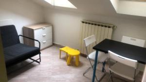 um quarto com uma mesa e uma cadeira e um banco amarelo em ¡PRECIOSO ATICO EN LA PLAZA MAYOR! em León