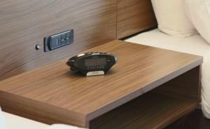 a alarm clock sitting on a wooden table in a bed at Kalika Hotel in Niagara Falls