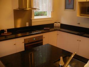 a kitchen with a black counter top and a sink at Brockworth Cottage in Christchurch