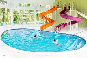 een groep mensen in een zwembad met glijbanen bij Hotel Mil Flores in Bragança Paulista