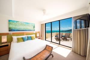 a hotel room with a large bed and a large window at Pinnacles Resort in Airlie Beach