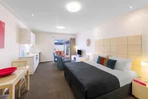 a hotel room with a bed and a desk and a kitchen at Nesuto Geraldton in Geraldton