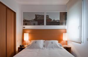 a bedroom with a bed with two lamps and a window at Apartamentos Eslava in Seville