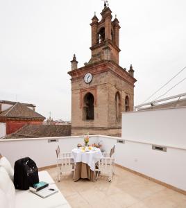a table on the roof of a building with a clock tower at Apartamentos Eslava in Seville