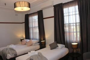 2 bedden in een hotelkamer met ramen bij Guildford Hotel in Guildford