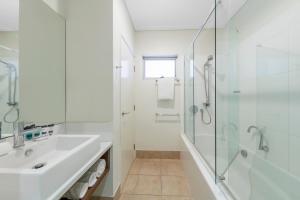 a white bathroom with a sink and a shower at Nesuto Geraldton in Geraldton