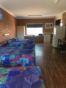 Zimmer mit 4 Betten und einer Küche mit Kühlschrank. in der Unterkunft Coonamble Motel in Coonamble