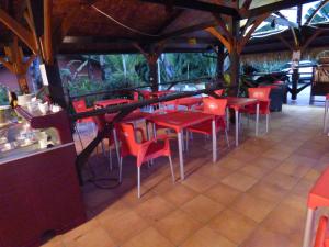 a restaurant with red tables and red chairs at Hotel La Marmotte in Matoury