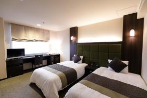 a hotel room with two beds and a desk at Hotel Binario Saga Arashiyama in Kyoto