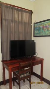 a flat screen tv on a wooden table in front of a window at AC Room 2 Persons Hospedaje Don Wilfredo in San Juan del Sur