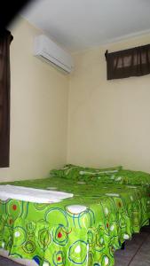 twee bedden in een kamer met een groene deken bij AC Room 2 Persons Hospedaje Don Wilfredo in San Juan del Sur