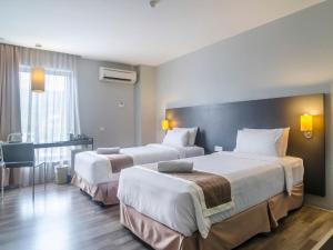 a hotel room with two beds and a television at The Leverage Business Hotel - Rawang in Rawang