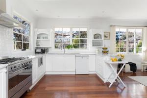 a white kitchen with white cabinets and a table at Bowral Escape in Burradoo