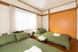 東京にあるK&K Apartment #301の緑のベッド2台と窓が備わる客室です。