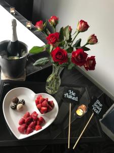 a table with a plate of strawberries and a vase with roses at Spa Suites at RAVEN in Hepburn Springs