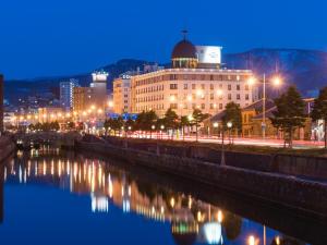 a city lit up at night next to a river at Hotel Nord Otaru in Otaru