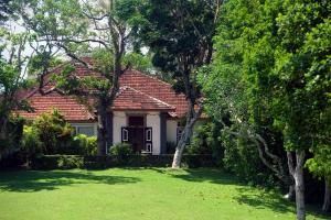 a white house with a red roof and a yard at Lunuganga Estate in Bentota