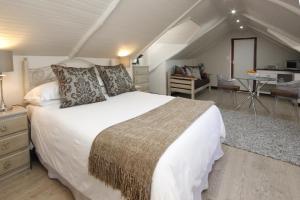 Un dormitorio con una gran cama blanca y una mesa en The Potting Shed Guest House, en Hermanus