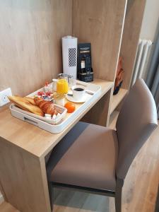 un vassoio di prodotti per la colazione su un tavolo con una sedia di Hôtel Mary's - Caen Centre Gare Sncf a Caen