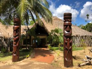 a house with two totem poles in front of it at Kanua Tera Ecolodge in Goro
