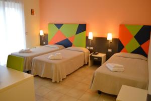 Habitación de hotel con 3 camas y paredes coloridas en La Lanterna Hotel en Rometta Marea