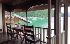 een tafel en stoelen op een balkon met uitzicht op het water bij Ricos Beach Cottages in El Nido