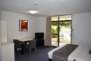 Cette chambre comprend un lit, un bureau et une table. dans l'établissement Roundhouse Motel, à Peterborough