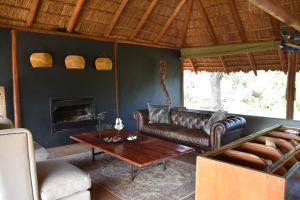 a living room with a leather couch and a table at Koro Island Camp in Mathathane