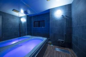 a blue bathroom with a tub and a shower at Hotel Noah Resort Sakuranomiya (Adult Only) in Osaka