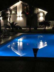 een blauw zwembad 's nachts met een huis op de achtergrond bij B&B Villa Elena in Furci Siculo
