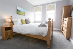 a bedroom with a bed and a dresser and two windows at Fernleigh in Robin Hood's Bay