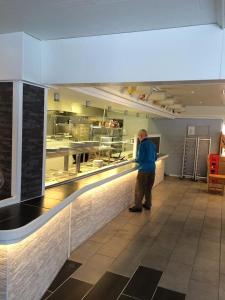 a man standing at a counter in a kitchen at Motell Trafikanten in Bygdeå