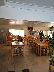 a restaurant with wooden tables and chairs and a person sitting at at Motell Trafikanten in Bygdeå