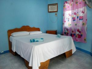 ein Schlafzimmer mit einem Bett mit einer weißen Tagesdecke in der Unterkunft John Lhea Beach Cottages in Siquijor