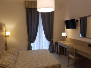 a hotel room with a bed and a desk and a window at Albergo Degli Amici in Monterosso al Mare