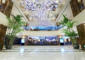 eine Lobby mit einem Kronleuchter und Palmen in einem Gebäude in der Unterkunft Xiamen Airlines Lakeside Hotel in Xiamen