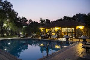 a swimming pool with a restaurant in the background at night at Doga Apartments in Kayakoy
