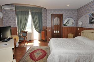 - une chambre avec un lit, un bureau et une télévision dans l'établissement Hotel Fossati, à Triuggio