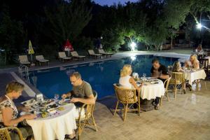 a group of people sitting at tables by a pool at Doga Apartments in Kayakoy