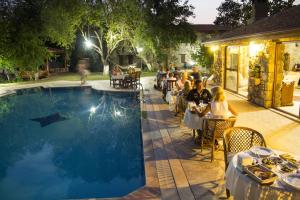 a group of people sitting at tables next to a pool at Doga Apartments in Kayakoy