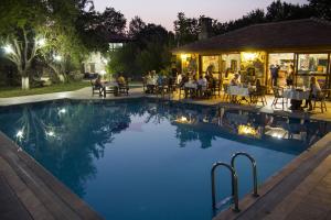 a pool at a restaurant at night with people sitting at Doga Apartments in Kayakoy