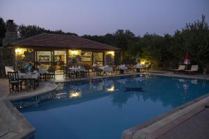 a pool with tables and chairs and a restaurant at Doga Apartments in Kayakoy